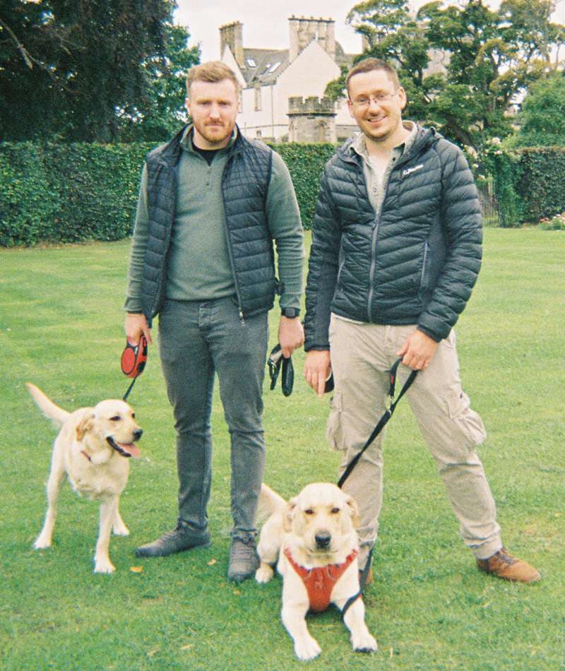 Two Storm employees each with their dogs in a castle garden setting